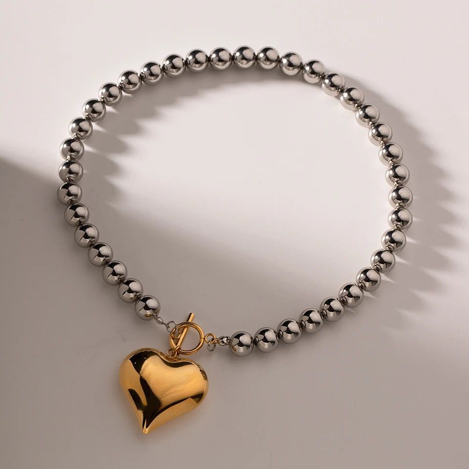 Collar bicolor con cuentas redondas y dije de corazón.